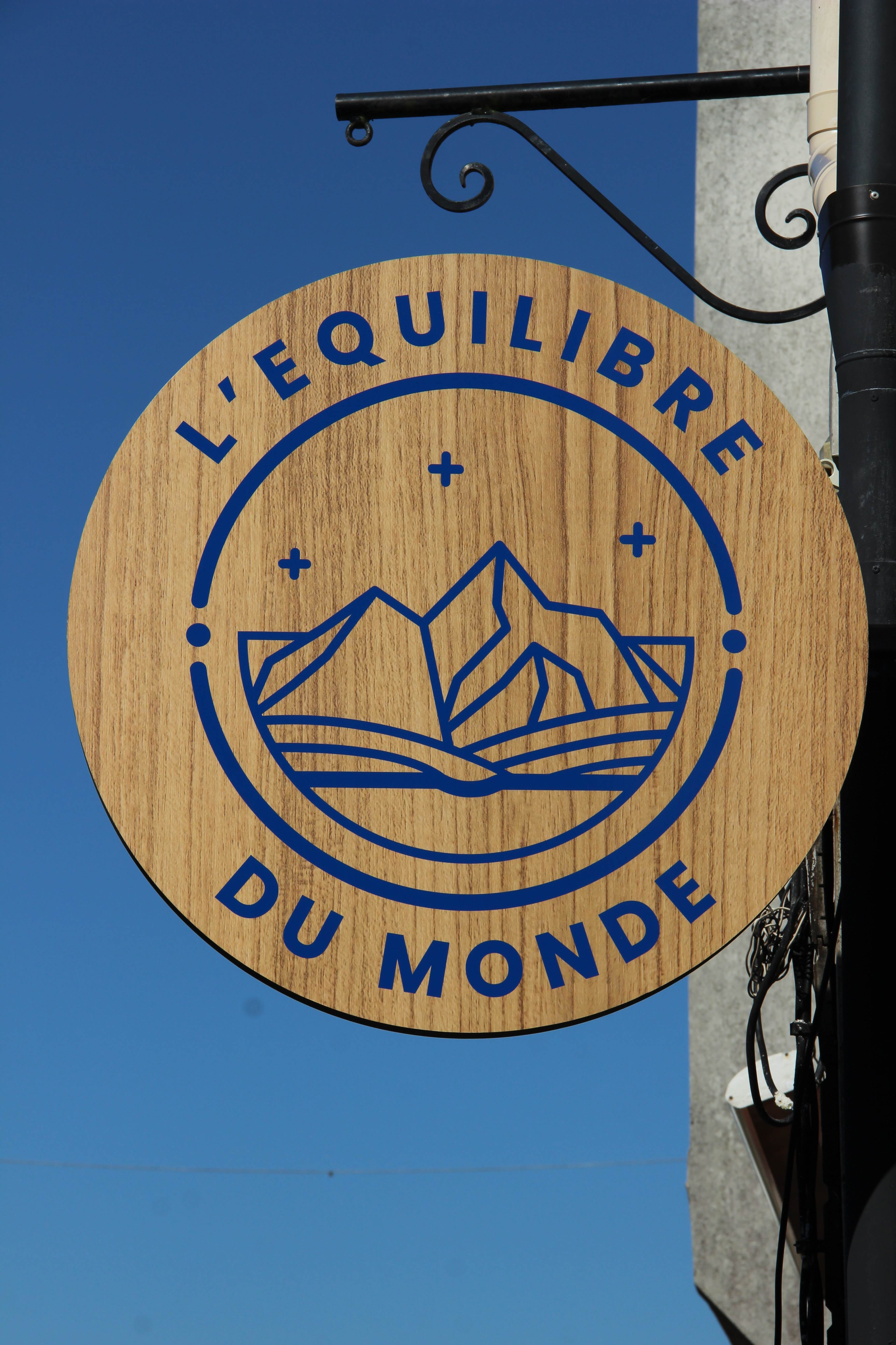 Logo de la librairie salon de thé café galerie d'art, L'Equilibre du monde, à Saint-Renan présentant un livre s'ouvrant sur une montagne et des étoiles